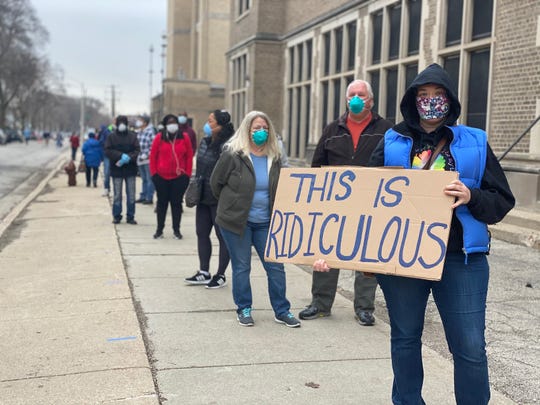 Photo of a long line outside a Wisconsin polling place; one person holds a sign that says "This is ridiculous" 